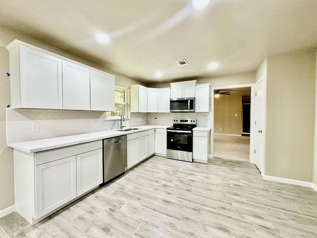 kitchen with decorative backsplash, appliances with stainless steel finishes, white cabinetry, and sink