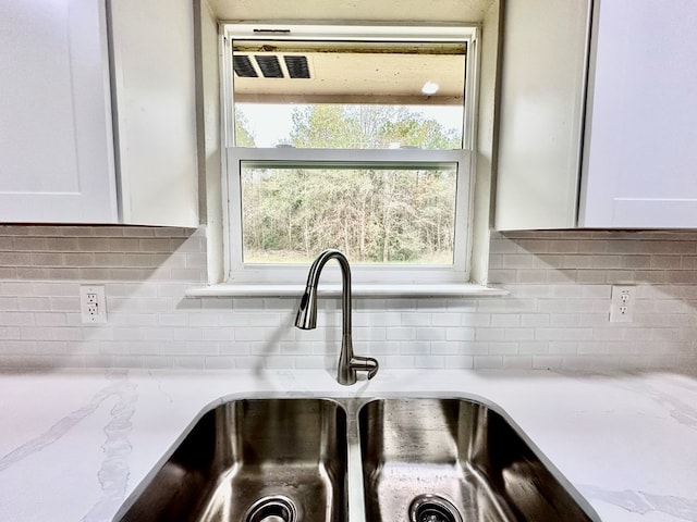 details featuring light stone counters, white cabinetry, and sink