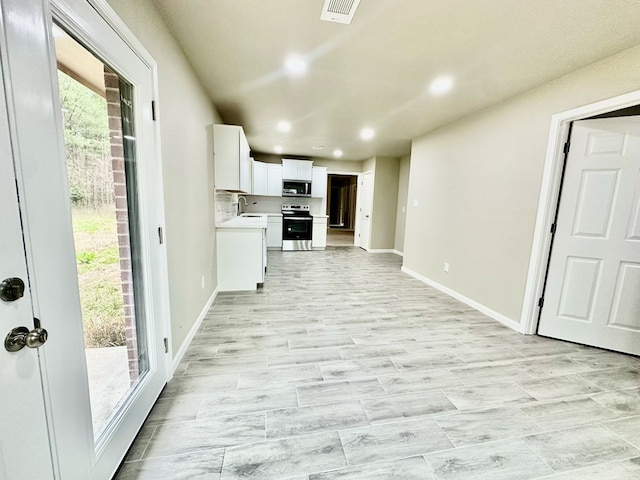 kitchen featuring decorative backsplash, appliances with stainless steel finishes, white cabinetry, and sink