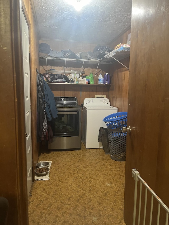 washroom featuring washing machine and clothes dryer, wooden walls, carpet floors, and a textured ceiling