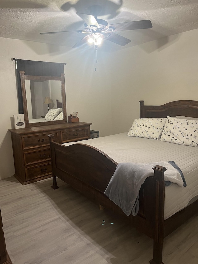 bedroom featuring ceiling fan, light wood-type flooring, and a textured ceiling