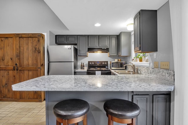 kitchen featuring stainless steel appliances, a kitchen bar, gray cabinetry, and kitchen peninsula