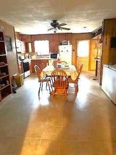 dining room featuring a ceiling fan and wooden walls