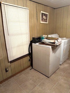 clothes washing area featuring laundry area, washer and clothes dryer, and wooden walls