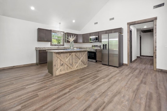 kitchen featuring stainless steel appliances, light countertops, dark brown cabinets, light wood-style flooring, and baseboards