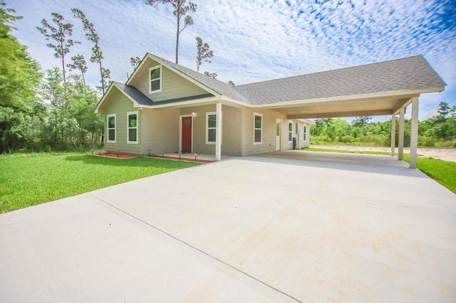 view of front facade with driveway, a front yard, roof with shingles, and a carport