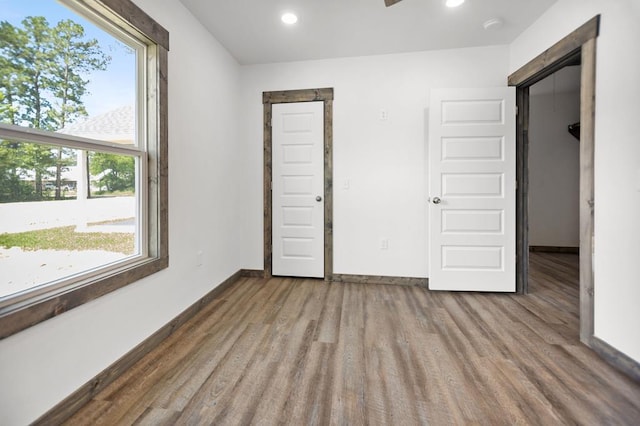 unfurnished bedroom featuring wood finished floors, multiple windows, recessed lighting, and baseboards