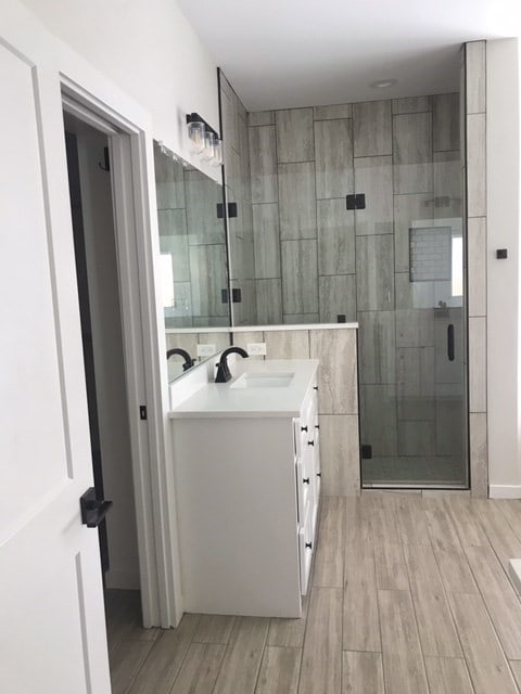 bathroom with hardwood / wood-style flooring, vanity, and a shower with door