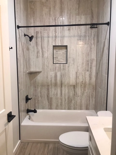 full bathroom featuring tiled shower / bath, toilet, vanity, and hardwood / wood-style flooring