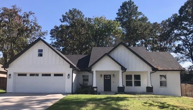 modern farmhouse style home featuring a front yard and a garage