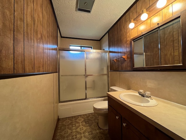 full bathroom with bath / shower combo with glass door, a textured ceiling, tile patterned flooring, toilet, and wood walls