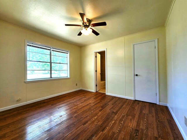 unfurnished bedroom featuring dark wood-type flooring, ornamental molding, and ceiling fan