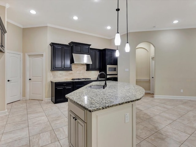 kitchen featuring a center island with sink, sink, ornamental molding, appliances with stainless steel finishes, and light stone counters