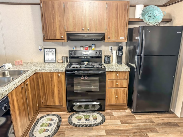 kitchen with sink, black appliances, and light hardwood / wood-style floors