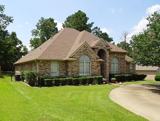 4805 Champions Dr, Lufkin, TX 75901 - view of front of house featuring brick siding, a front lawn, central AC, and a shingled roof