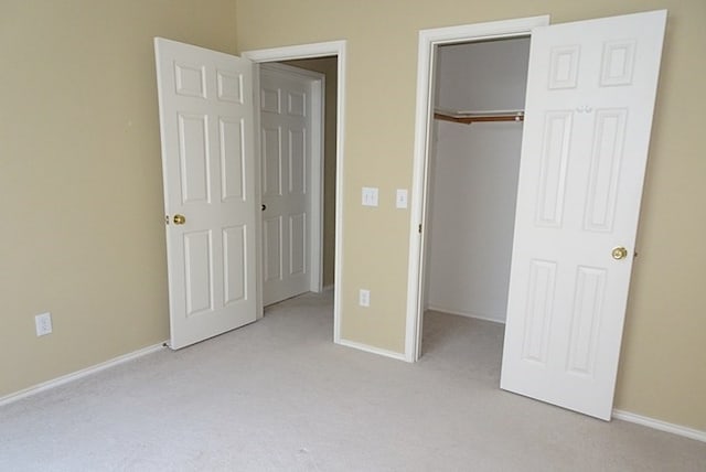 unfurnished bedroom with light carpet, a walk in closet, and a closet