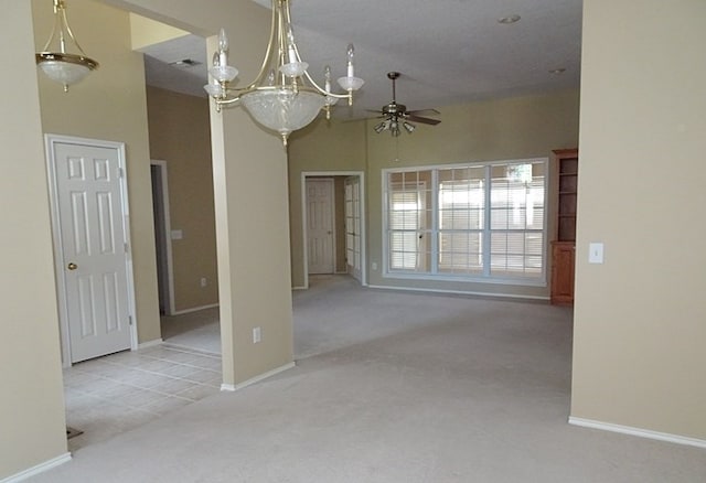 spare room with a high ceiling, ceiling fan with notable chandelier, and light colored carpet