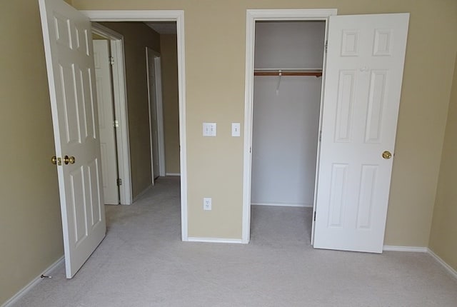 unfurnished bedroom featuring a closet and light colored carpet