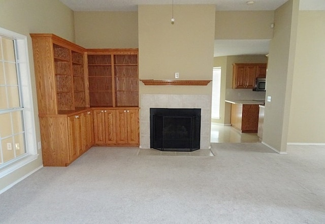 unfurnished living room with light colored carpet and a tiled fireplace