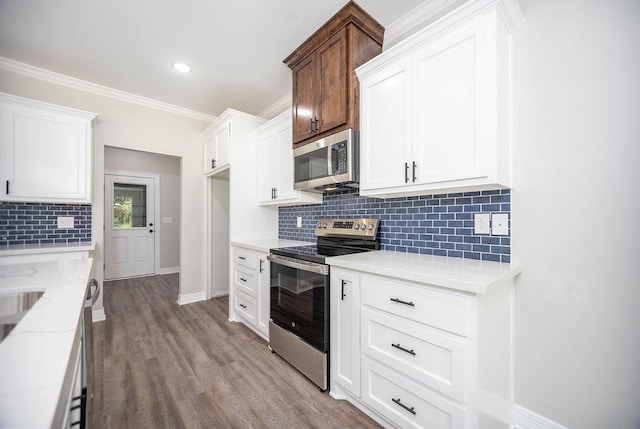 kitchen with light stone countertops, white cabinets, stainless steel appliances, decorative backsplash, and light hardwood / wood-style floors