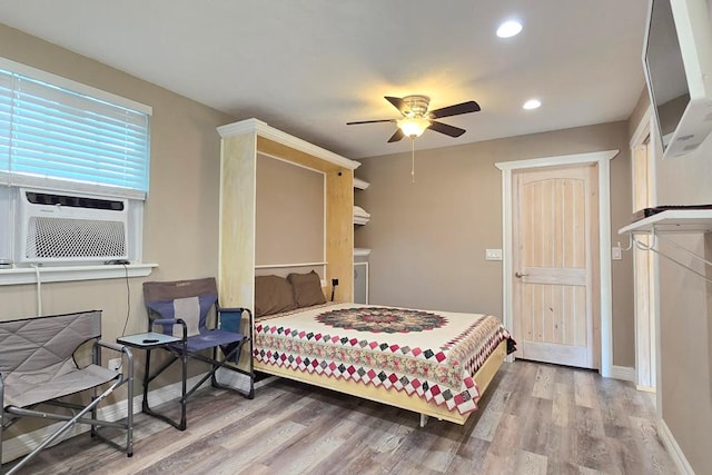 bedroom featuring ceiling fan, cooling unit, and light hardwood / wood-style flooring