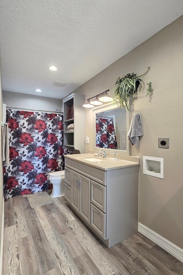 bathroom featuring walk in shower, a textured ceiling, vanity, hardwood / wood-style flooring, and toilet