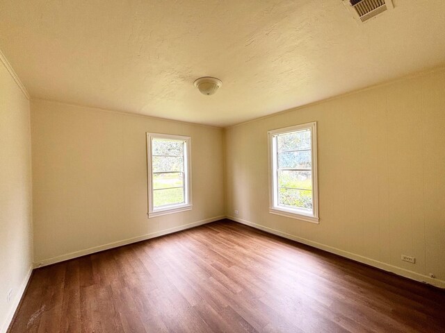 spare room with a wealth of natural light, hardwood / wood-style floors, and a textured ceiling