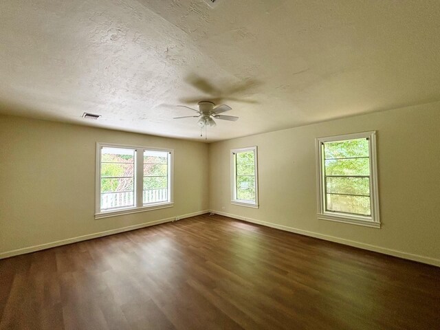 spare room featuring a textured ceiling, dark hardwood / wood-style flooring, a wealth of natural light, and ceiling fan