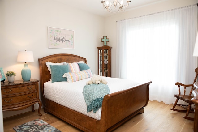 bedroom featuring an inviting chandelier and light wood-type flooring