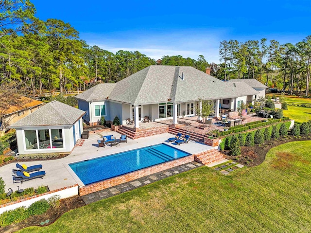 back of house featuring outdoor lounge area, a patio, and a lawn