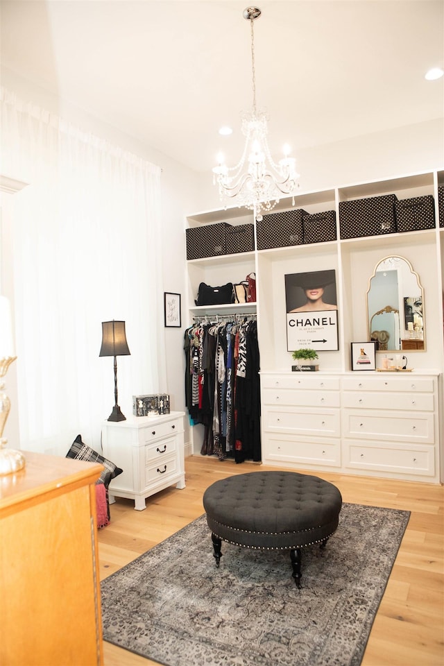 spacious closet featuring a chandelier and light hardwood / wood-style flooring