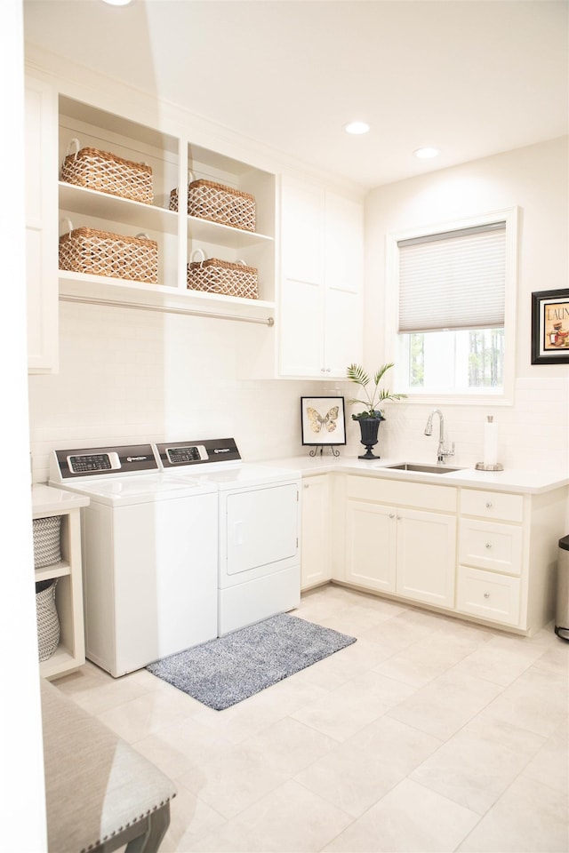 clothes washing area featuring cabinets, sink, light tile patterned floors, and washer and dryer