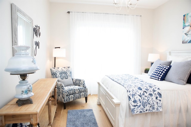 bedroom with light hardwood / wood-style floors, an inviting chandelier, and multiple windows