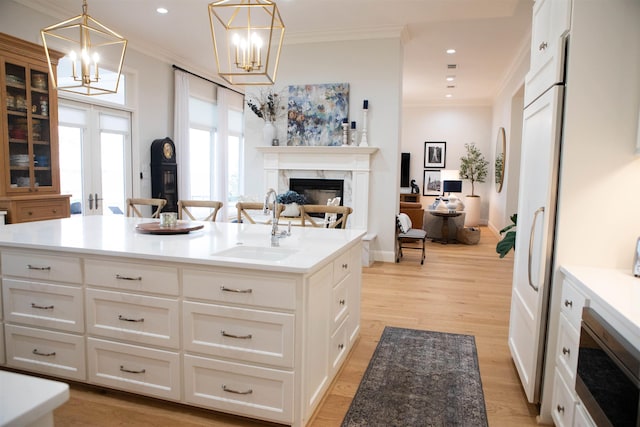 kitchen with a high end fireplace, crown molding, a center island, light hardwood / wood-style floors, and white cabinetry