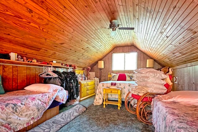 carpeted bedroom featuring lofted ceiling, wooden ceiling, and wooden walls