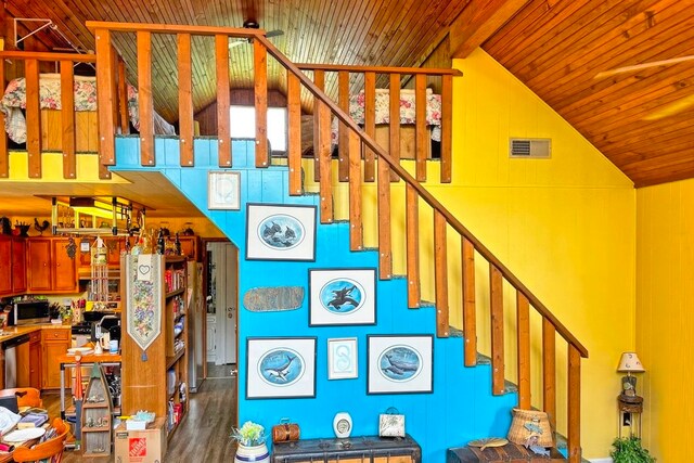 stairs featuring beam ceiling, ceiling fan, wood ceiling, and hardwood / wood-style flooring