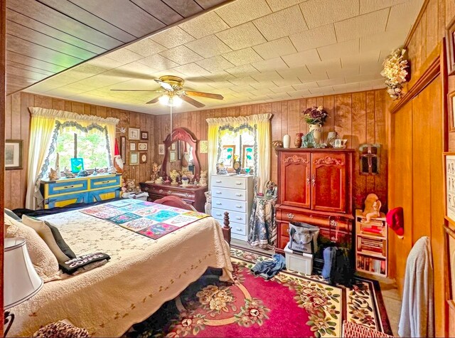 bedroom featuring ceiling fan and wood walls