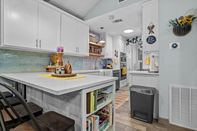 kitchen featuring a breakfast bar, white cabinets, tasteful backsplash, decorative light fixtures, and kitchen peninsula