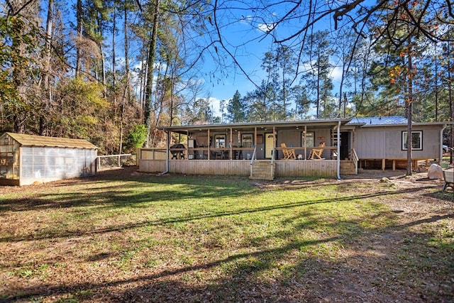 back of property with covered porch, an outdoor structure, and a lawn