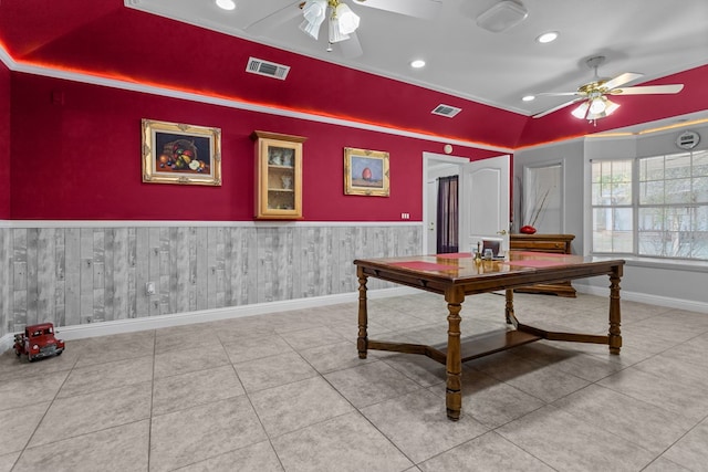 tiled dining room featuring crown molding, wooden walls, and ceiling fan