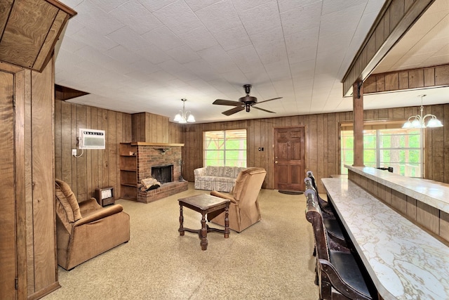 carpeted living room with a fireplace, ceiling fan with notable chandelier, a wall unit AC, and wooden walls