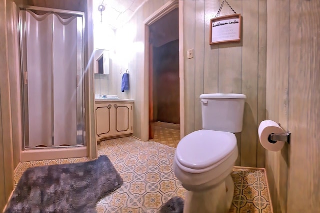 bathroom featuring tile patterned floors, wood walls, toilet, a shower with door, and vanity