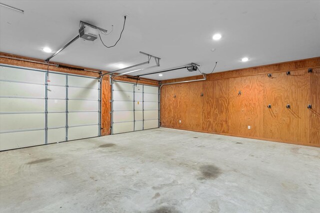 garage featuring a garage door opener and wooden walls