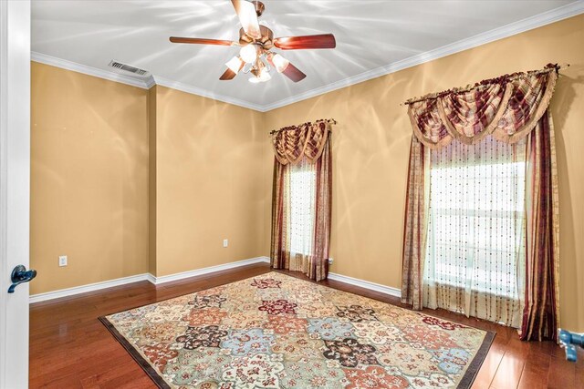 empty room featuring crown molding, ceiling fan, and dark wood-type flooring