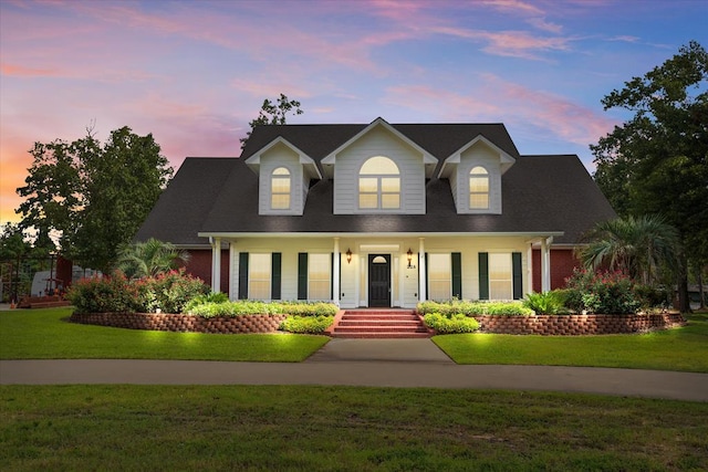 new england style home featuring a yard and a porch