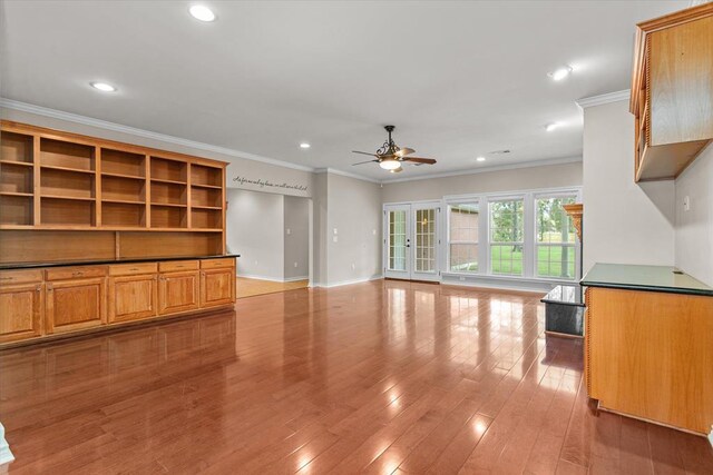 unfurnished living room with crown molding, ceiling fan, and light wood-type flooring