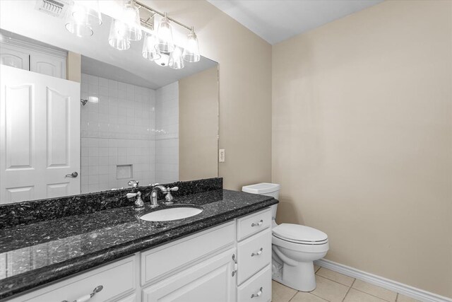 bathroom featuring tile patterned floors, vanity, tiled shower, and toilet