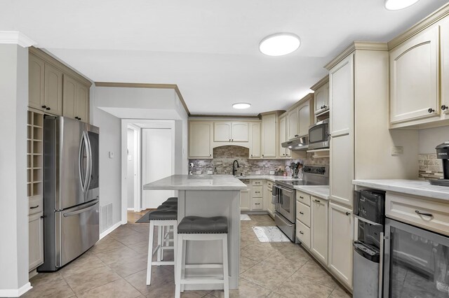 kitchen featuring stainless steel appliances, wine cooler, cream cabinetry, a breakfast bar, and a kitchen island