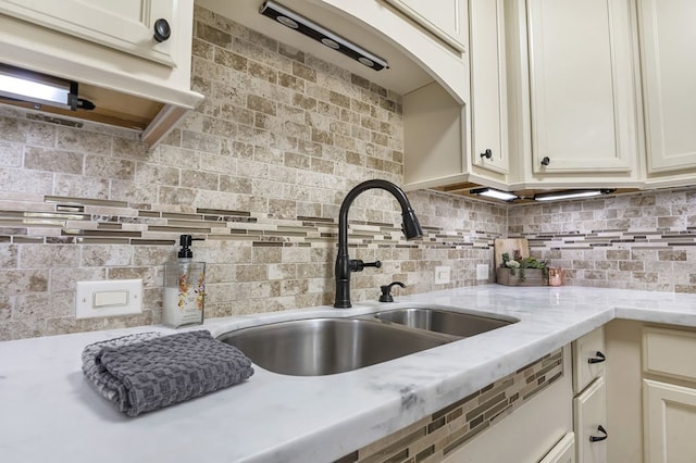 kitchen featuring decorative backsplash, light stone counters, and sink