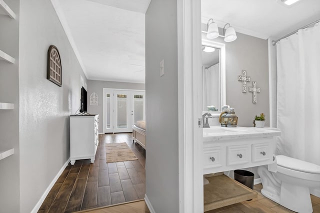 2528 Sam Rayburn Pkwy, Brookeland, TX 75931 - bathroom with ornamental molding, toilet, vanity, baseboards, and wood finished floors